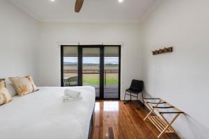 a white bedroom with a bed and a chair at Farmstay -LJHooker Yamba in Maclean