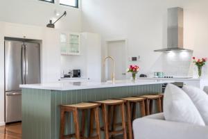 a kitchen with a green island with bar stools at Farmstay -LJHooker Yamba in Maclean
