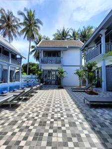 um pátio de uma casa com bancos e palmeiras em LuangPrabang Pearl Hotel em Luang Prabang