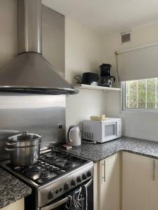 a kitchen with a stove and a microwave at Casa Country Golf Club, Pagos en USD in Gualeguaychú