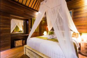 Schlafzimmer mit einem Bett mit Moskitonetz in der Unterkunft Taman Sari Villa, Nusa Lembongan in Nusa Lembongan