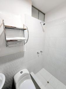 a white bathroom with a toilet and a sink at Departamento familiar en Huacachina in Ica