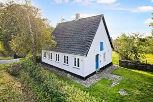 a small white house with a black roof at Holmegrd - A Cozy Country House On The Outskirts Of Sby in Soby Mark