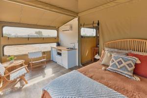 a bedroom with a bed and a kitchen in a tent at Willow Wood Glamping Retreat in Broadwater