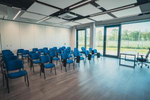 Pokój z niebieskimi krzesłami, stołami i oknami w obiekcie Centrum Szkoleniowo - Noclegowe HHM HEGELMANN 