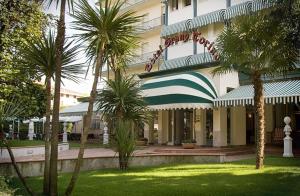 a hotel with palm trees in front of a building at Hotel Grand Torino in Abano Terme