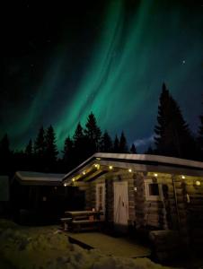 eine Hütte mit den Nordlichtern am Himmel in der Unterkunft Mökki Cottages RukaTupa in Ruka