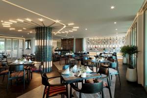 a restaurant with tables and chairs in a room at Wyndham Grand Nai Harn Beach Phuket in Nai Harn Beach