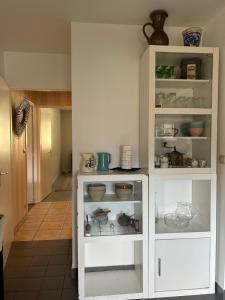 a white cabinet filled with dishes and bowls at Appartement 109 in Sallanches +8 photos