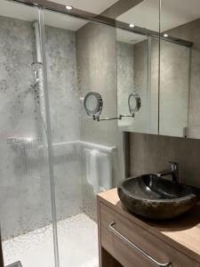 een badkamer met een wastafel en een glazen douche bij Appartement 109 in Sallanches