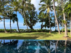 a pool with palm trees and the ocean in the background at Amatapura Beachfront Villa 10 , SHA Certified in Ao Nam Mao