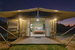 Zelt mit einem Bett und zwei Stühlen auf einer Terrasse in der Unterkunft Willow Wood Glamping Retreat in Broadwater