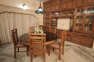 a dining room with a wooden table and chairs at Metropolitan Serviced Villa in Cochin