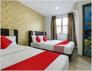 two beds in a hotel room with red pillows at NS INN Hotel in Melaka