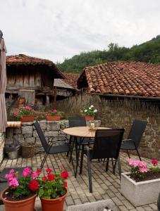 um pátio com uma mesa, cadeiras e flores em Hostal Remoña em Espinama