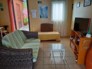 - un salon avec un canapé, une chaise et une télévision dans l'établissement Maison à Saint-Leu, vue panoramique sur l'océan à 2 minutes des plages, à Saint-Leu