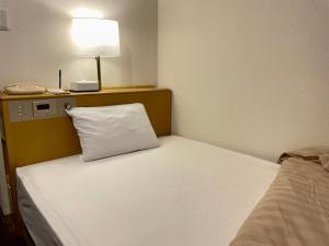 un letto con un cuscino bianco in una stanza di Sabae Daiichi Hotel a Sabae