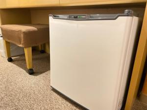 a white refrigerator under a desk with a chair at Sabae Daiichi Hotel in Sabae