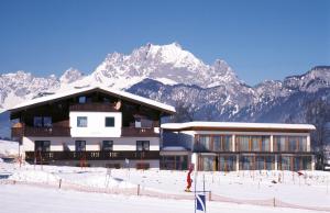 un bâtiment dans la neige avec des montagnes en arrière-plan dans l'établissement Apartments Aeon, à St. Johann in Tirol