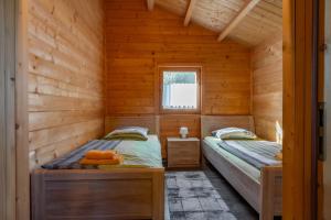 two beds in a log cabin with a window at Ferienpark Waldsiedlung in Großkoschen