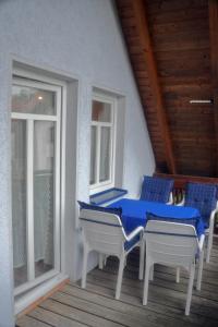 una mesa azul y sillas en un porche con ventanas en Ferienwohnung blaues Haus, en Bischofsheim an der Rhön