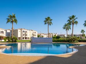 uma piscina com palmeiras e edifícios ao fundo em Paradise Palms, 2bed Apt W Pool em Mandria