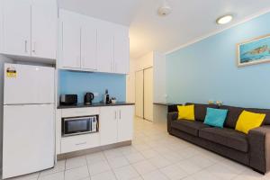 a living room with a couch and a kitchen at Ramada Spacious Studio Apartment with Pool Views in Port Douglas
