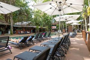 a row of chairs and umbrellas next to a pool at Ramada Spacious Studio Apartment with Pool Views in Port Douglas