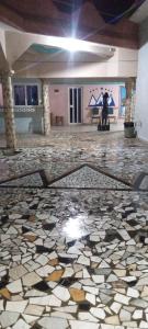 a room with a mosaic floor with a person sitting on a bench at Hôtel cœur des montagnes in Abomey