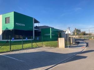 a green building with a fence in front of it at New Pension at ROTOR Brewery in Kunovice