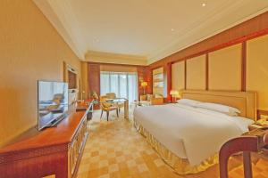 um quarto com uma cama e uma secretária com uma televisão em Shanghai Dongjiao State Guest Hotel em Xangai