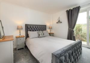 a bedroom with a large bed and a window at Pebbles in Abersoch