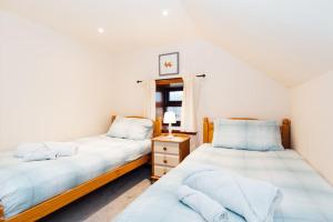 a bedroom with two beds and a window at The Barn @ Clauchan holiday Cottages in Gatehouse of Fleet