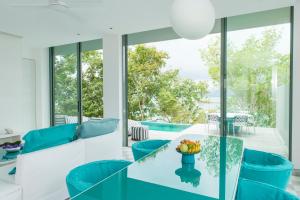 - un salon avec une table en verre et des chaises bleues dans l'établissement COMO Point Yamu, Phuket- SHA Extra Plus, à Ban Pa Khlok