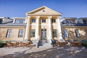 a building with tables and chairs in front of it at Skrunda Manor in Skrunda