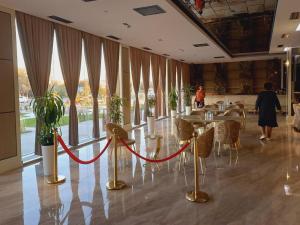 カルシにあるAstra hotelの赤いロープ付きのテーブルと椅子が備わるレストラン