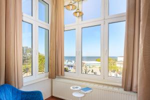 a room with windows with a view of the ocean at Strandhotel Preussenhof in Zinnowitz