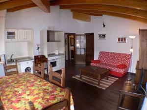 a living room with a red couch and a kitchen at 1g CASA DE LOS FERNANDEZ RAJO in Orihuela del Tremedal