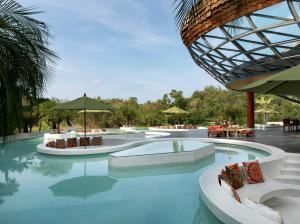 a pool with chairs and umbrellas in a resort at Wyndham Grand Nai Harn Beach Phuket in Nai Harn Beach