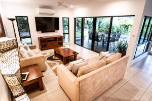 a living room with two couches and a tv at Chez Brolga in Port Douglas