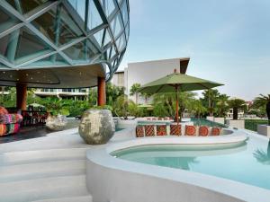 a pool at a resort with chairs and an umbrella at Wyndham Grand Nai Harn Beach Phuket in Nai Harn Beach