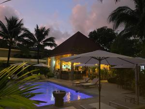 a swimming pool with umbrellas in front of a house at Lotus Bleu Resort & Restaurant in Rawai Beach