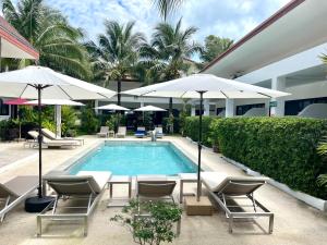 - une piscine avec des chaises et des parasols à côté d'un bâtiment dans l'établissement Lotus Bleu Resort & Restaurant, à Rawai Beach