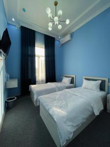 two beds in a room with blue walls at IMAM AZAM HOTEL in Samarkand