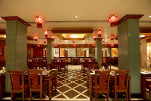 ein Restaurant mit Holztischen und Stühlen und Lichtern in der Unterkunft Breeze Residency in Tiruchchirāppalli