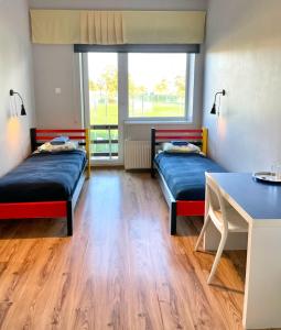 um quarto com 2 camas, uma secretária e uma mesa em Tamme staadioni hostel em Tartu