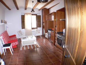 sala de estar con sofá rojo y cocina en 1 P Casa de los Fernandez Rajo, en Orihuela del Tremedal