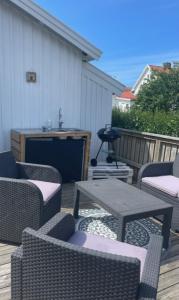 patio z krzesłami i stołami oraz telewizorem w obiekcie Gäststuga w mieście Grebbestad