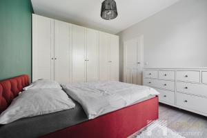 une chambre avec un lit, des armoires blanches et une tête de lit rouge dans l'établissement Fuzja IV by LookAp, à Łódź