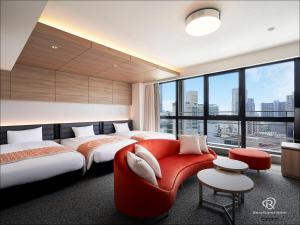 a hotel room with two beds and a red couch at Daiwa Roynet Hotel KOBE-SANNOMIYA PREMIER in Kobe